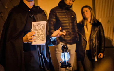 Guide holding lantern and illustration during Ghosts & Legends of Old Town Prague tour.