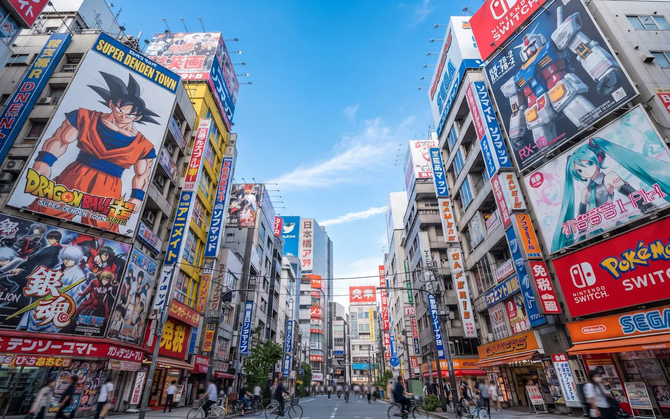 Osaka Den Den Town street with anime and gaming billboards, featuring Dragon Ball and Hatsune Miku.