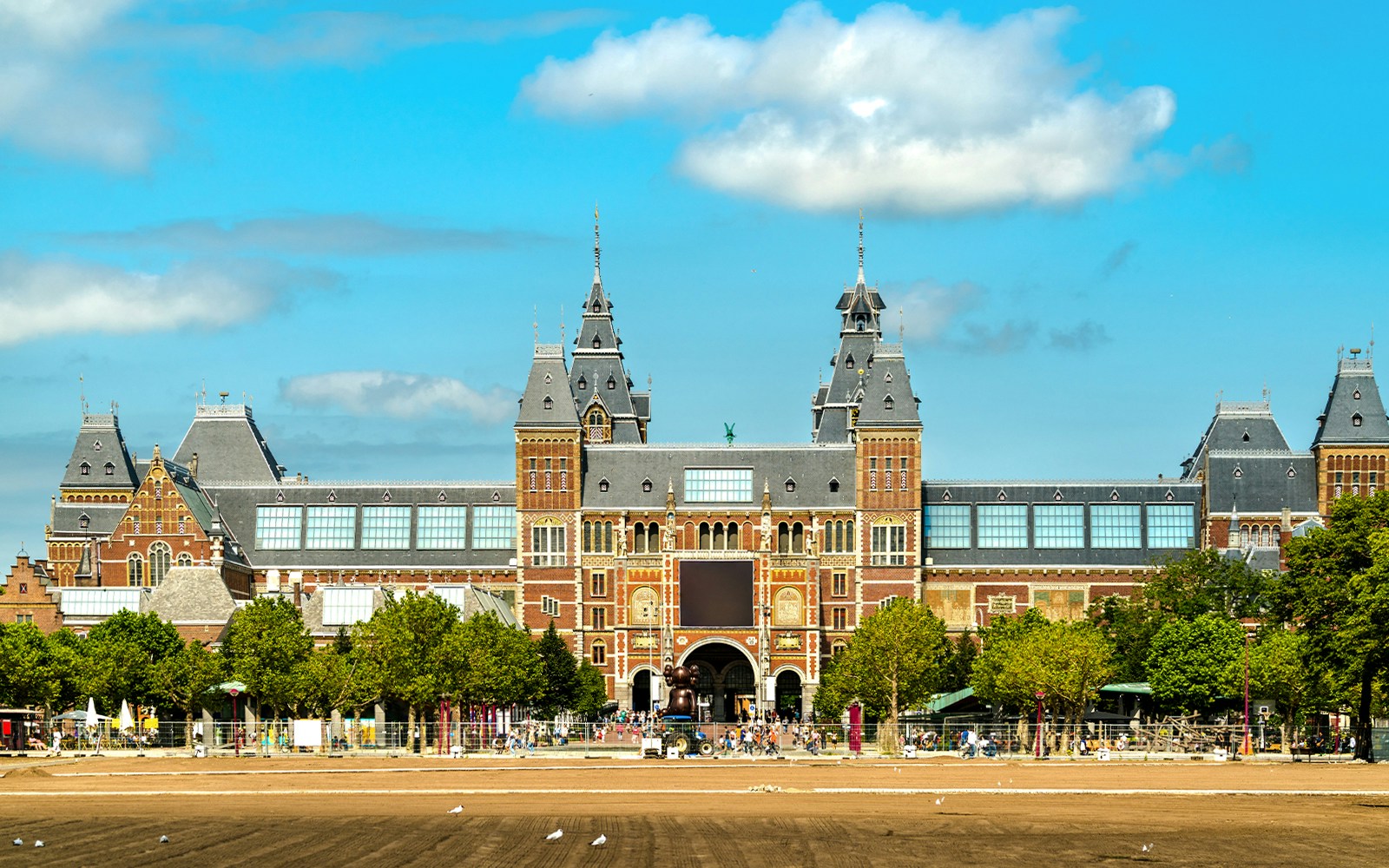 Rijksmuseum facade in Amsterdam under a blue sky, viewed from Museumplein.