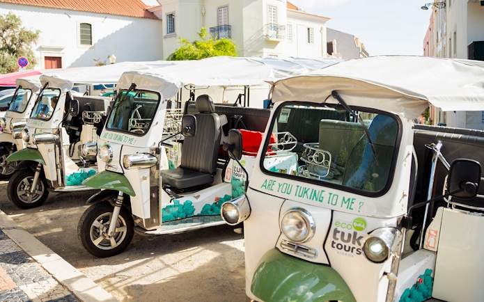Eco tuk tuk stand in Lisbon with parked vehicles ready for tours.