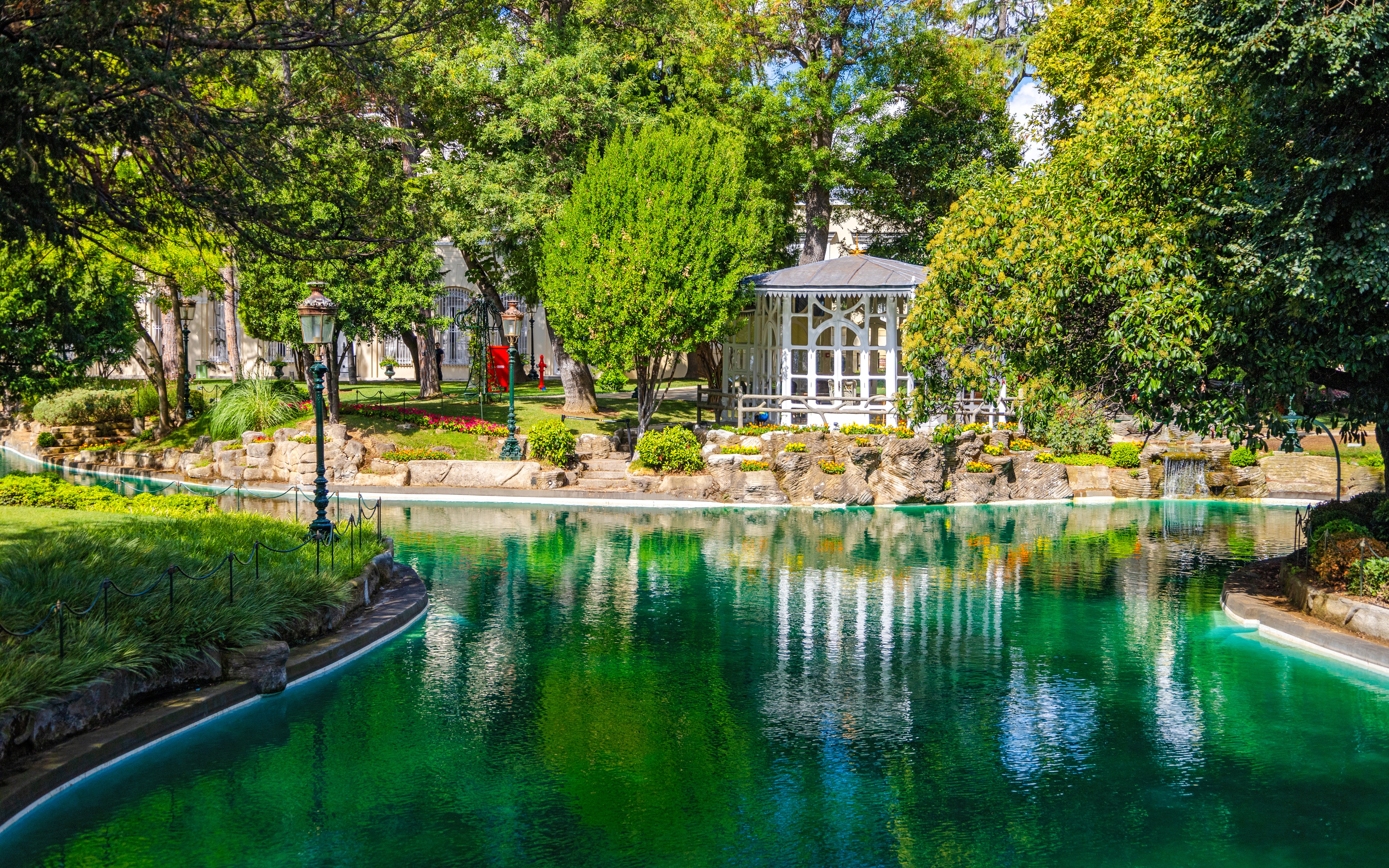 Exterior view of Yıldız Palace garden with pond and gazebo on a sunny day.