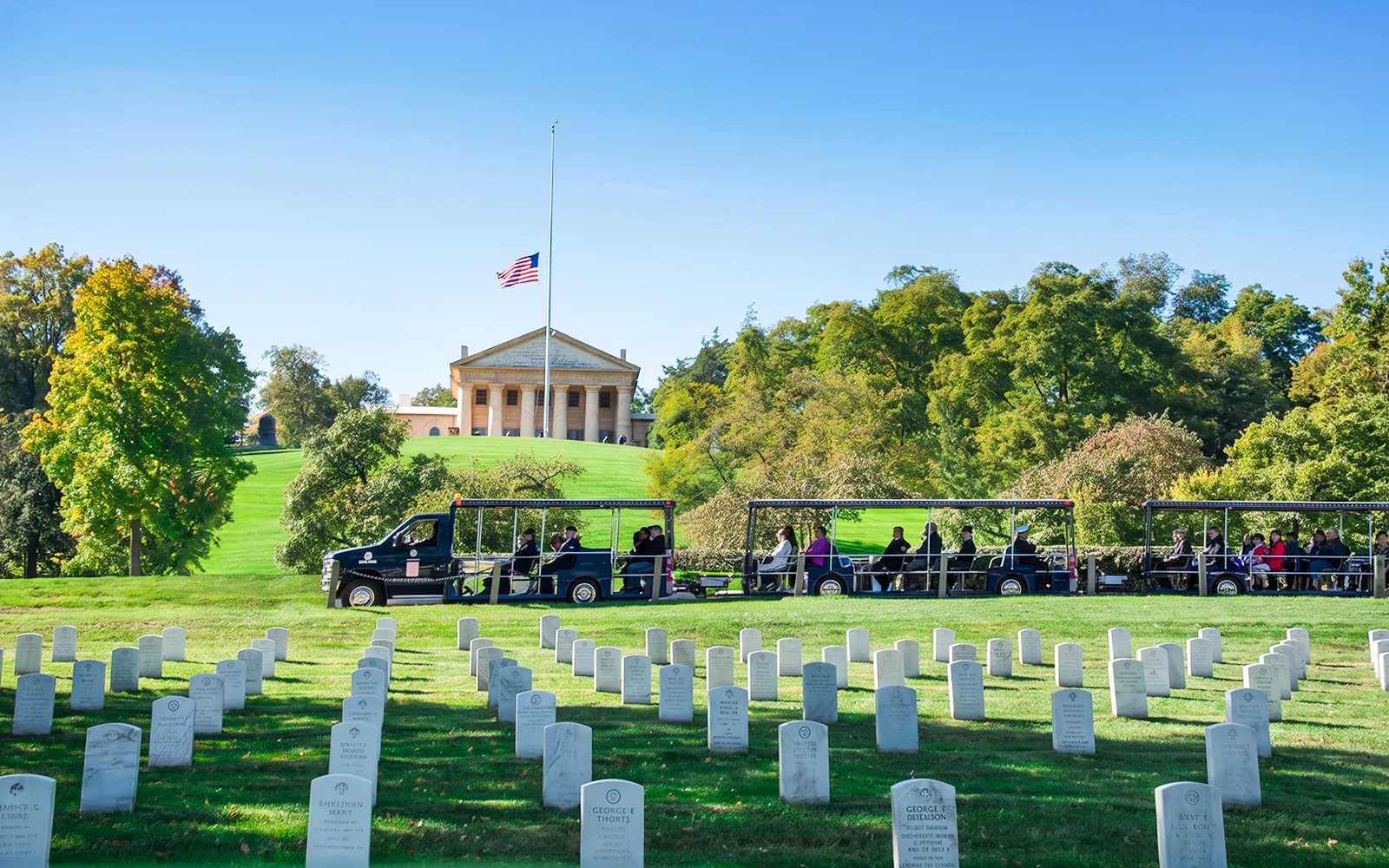 Tram tour passing through Arlington National Cemetery with Arlington House in the background.