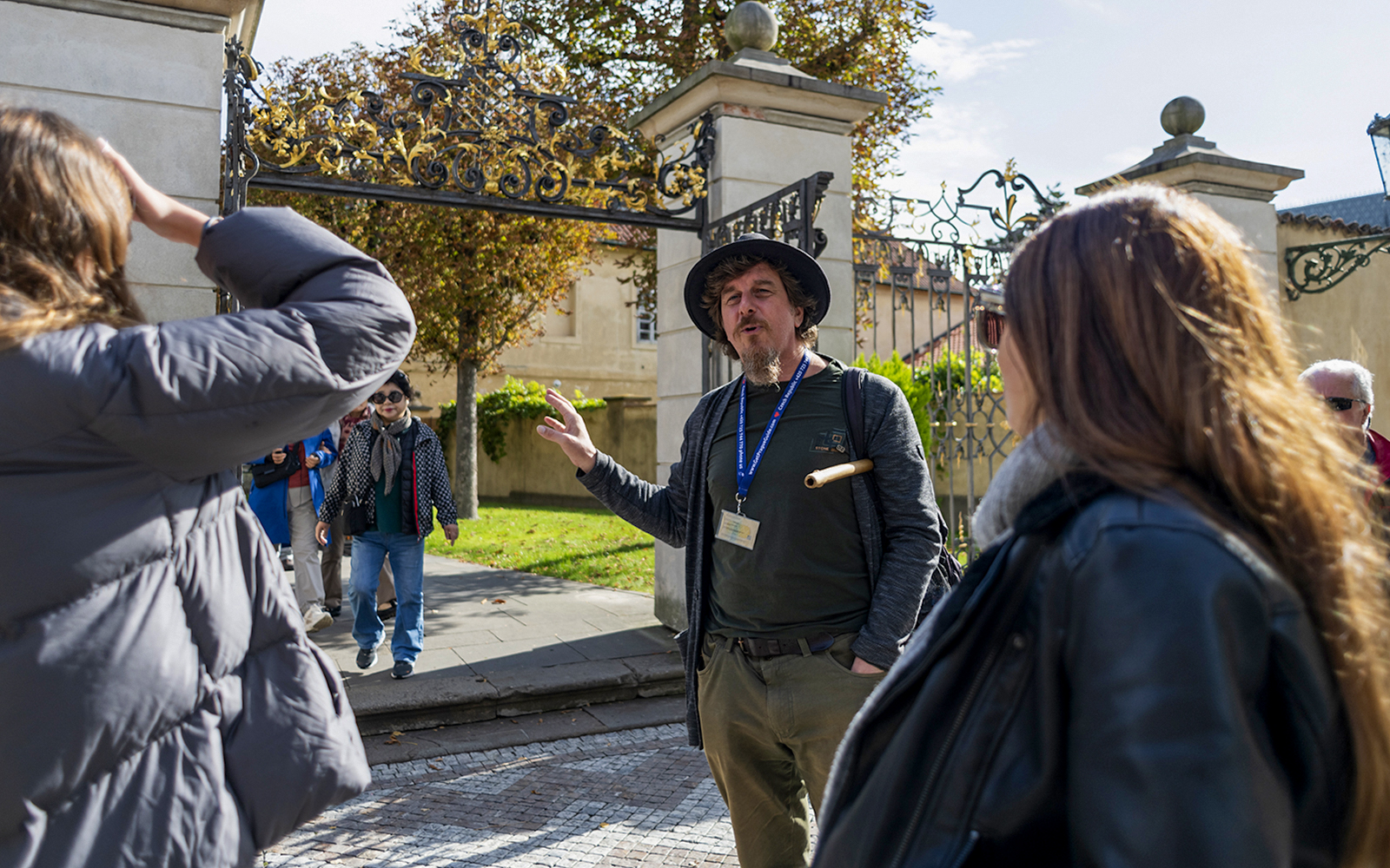 Tour guide explaining to tourists in front of Prague Castle gate.