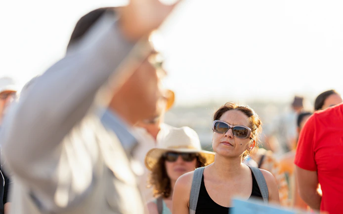 Tourists attentively listening to a guide's explanation outdoors.