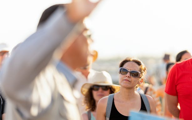 Tourists attentively listening to a guide's explanation outdoors.