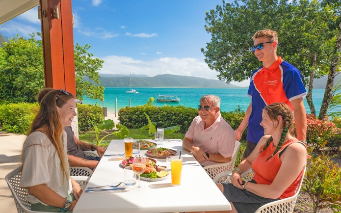 Tourists enjoying buffet lunch on Fitzroy Island with Great Barrier Reef view.