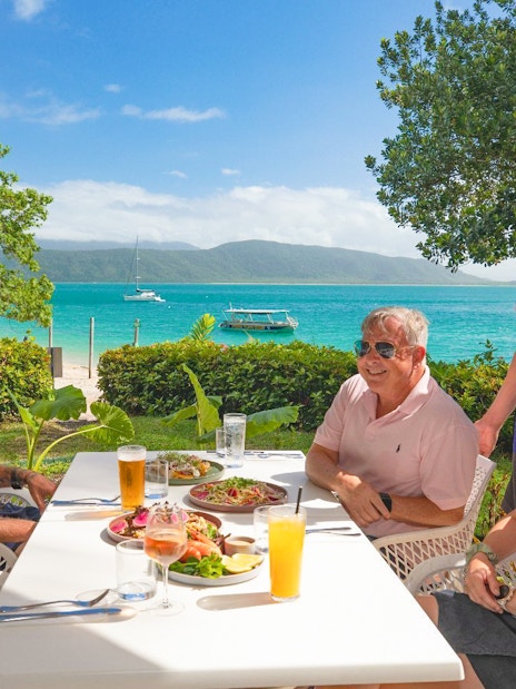 Tourists enjoying buffet lunch on Fitzroy Island with Great Barrier Reef view.