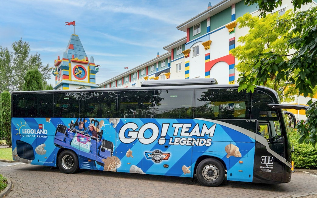 LEGOLAND® Windsor Resort Express bus parked near colorful hotel building.