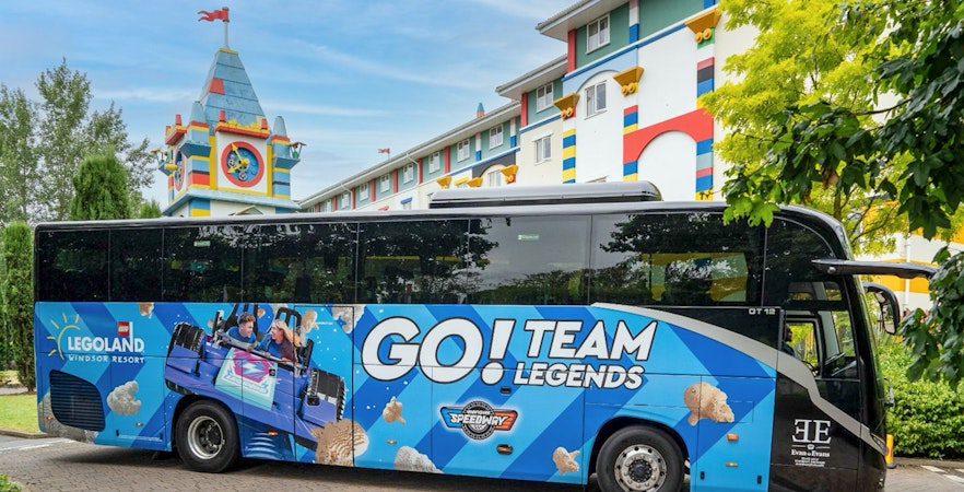 LEGOLAND® Windsor Resort Express bus parked near colorful hotel building.