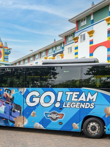 LEGOLAND® Windsor Resort Express bus parked near colorful hotel building.