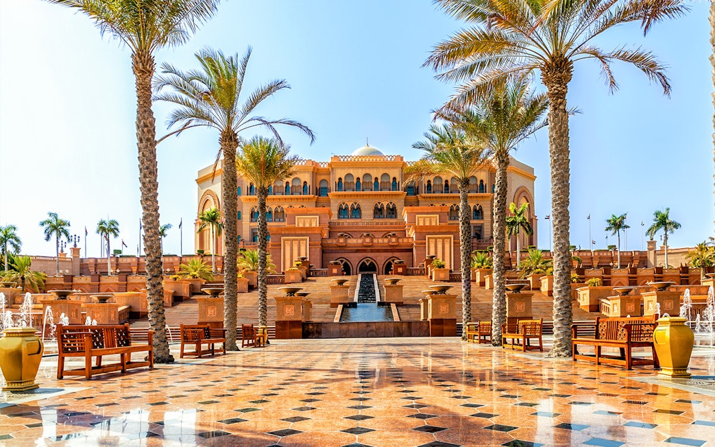 Emirates Palace Hotel entrance with palm trees, Abu Dhabi sightseeing tour.