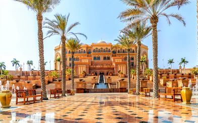 Emirates Palace Hotel entrance with palm trees, Abu Dhabi sightseeing tour.