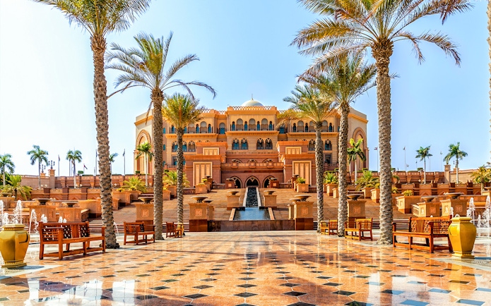 Emirates Palace Hotel entrance with palm trees, Abu Dhabi sightseeing tour.