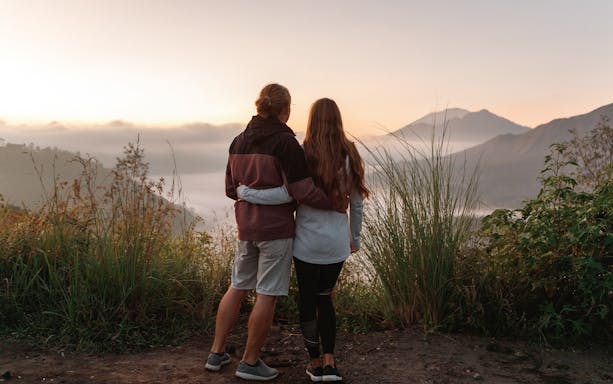 Couple admiring Mount Batur during sunrise trek in Bali.