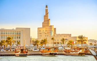 Doha Bay with spiral mosque and traditional boats, Corniche, Doha.