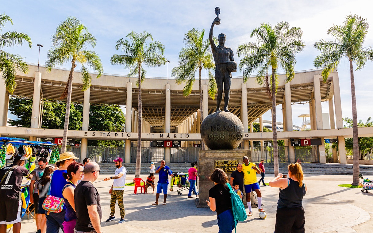 Statue of a footballer outside Maracanã Stadium, Rio de Janeiro, with tourists nearby.