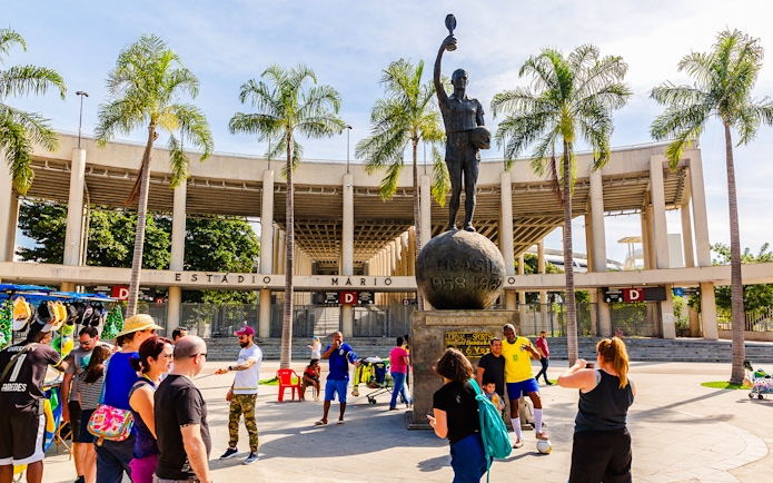 Statue of a footballer outside Maracanã Stadium, Rio de Janeiro, with tourists nearby.