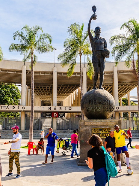 Statue of a footballer outside Maracanã Stadium, Rio de Janeiro, with tourists nearby.