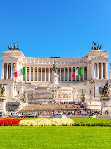 Altare della Patria in Rome with Italian flags and tourists exploring the monument.