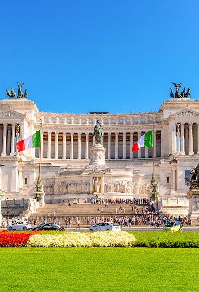 Altare della Patria in Rome with Italian flags and tourists exploring the monument.