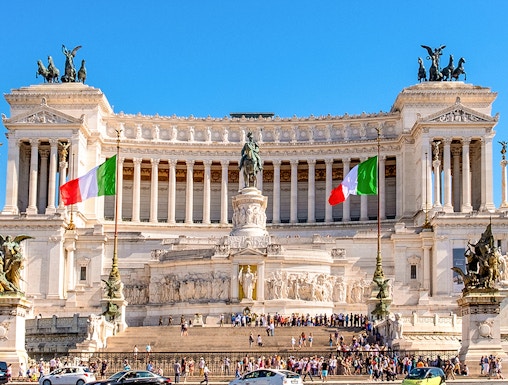 Altare della Patria in Rome with Italian flags and tourists exploring the monument.