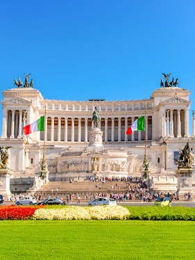 Altare della Patria in Rome with Italian flags and tourists exploring the monument.