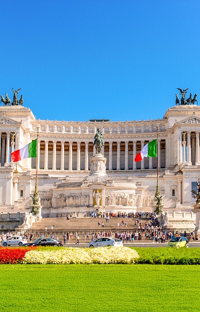 Altare della Patria in Rome with Italian flags and tourists exploring the monument.