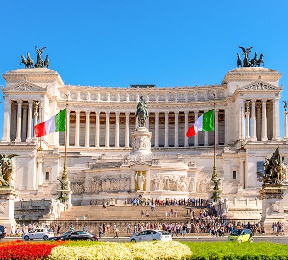 Altare della Patria in Rome with Italian flags and tourists exploring the monument.