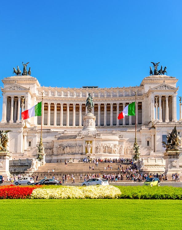Altare della Patria in Rome with Italian flags and tourists exploring the monument.