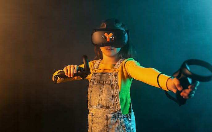 Child using YULLBE GO VR headset and controllers in immersive experience.