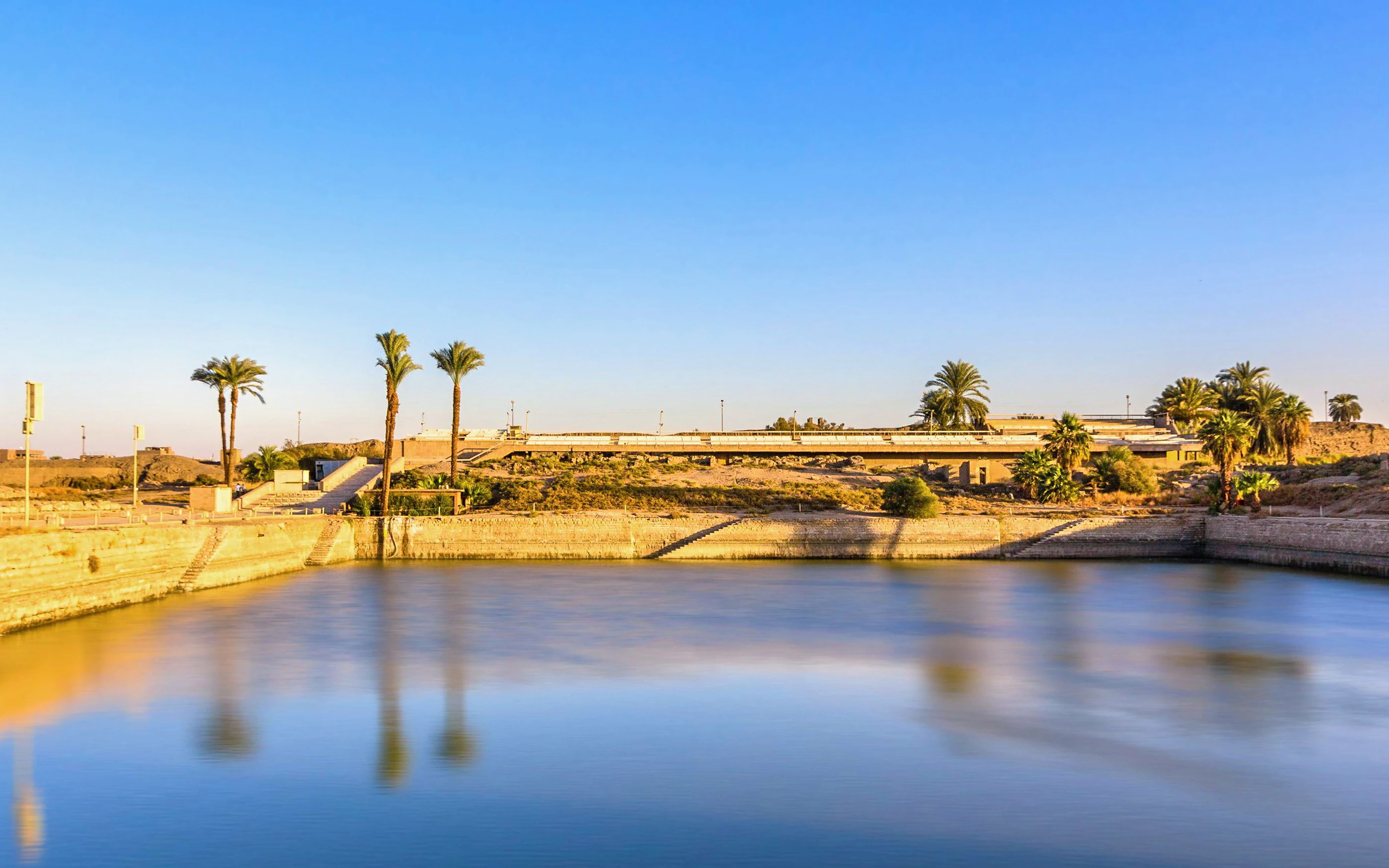 Sacred Lake at Karnak Temple with palm trees, Luxor, Egypt.