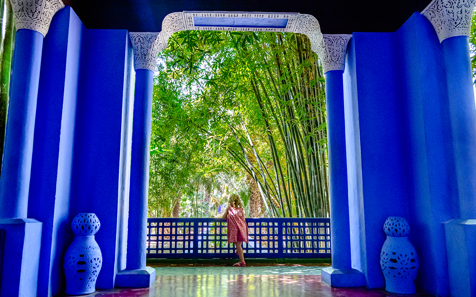 Child admiring bamboo through blue archway at Jardin Majorelle, Marrakech.
