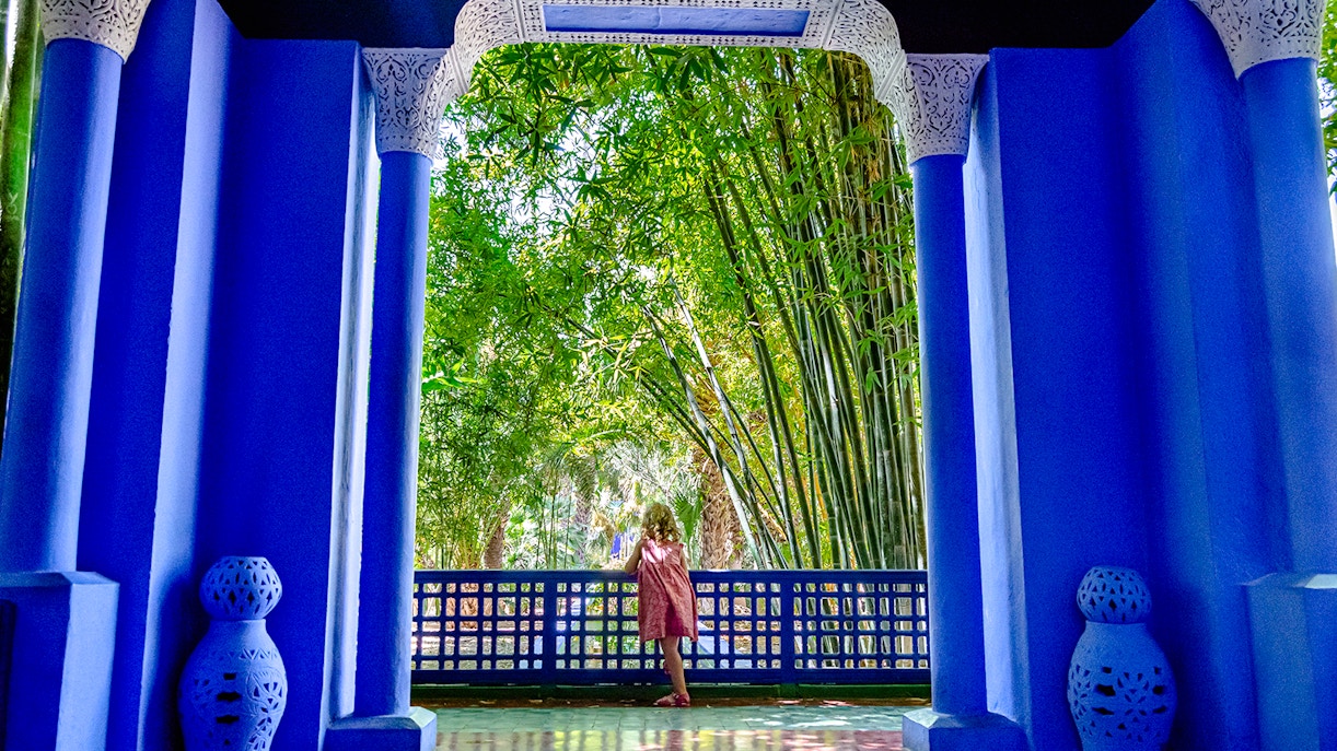 Child admiring bamboo through blue archway at Jardin Majorelle, Marrakech.