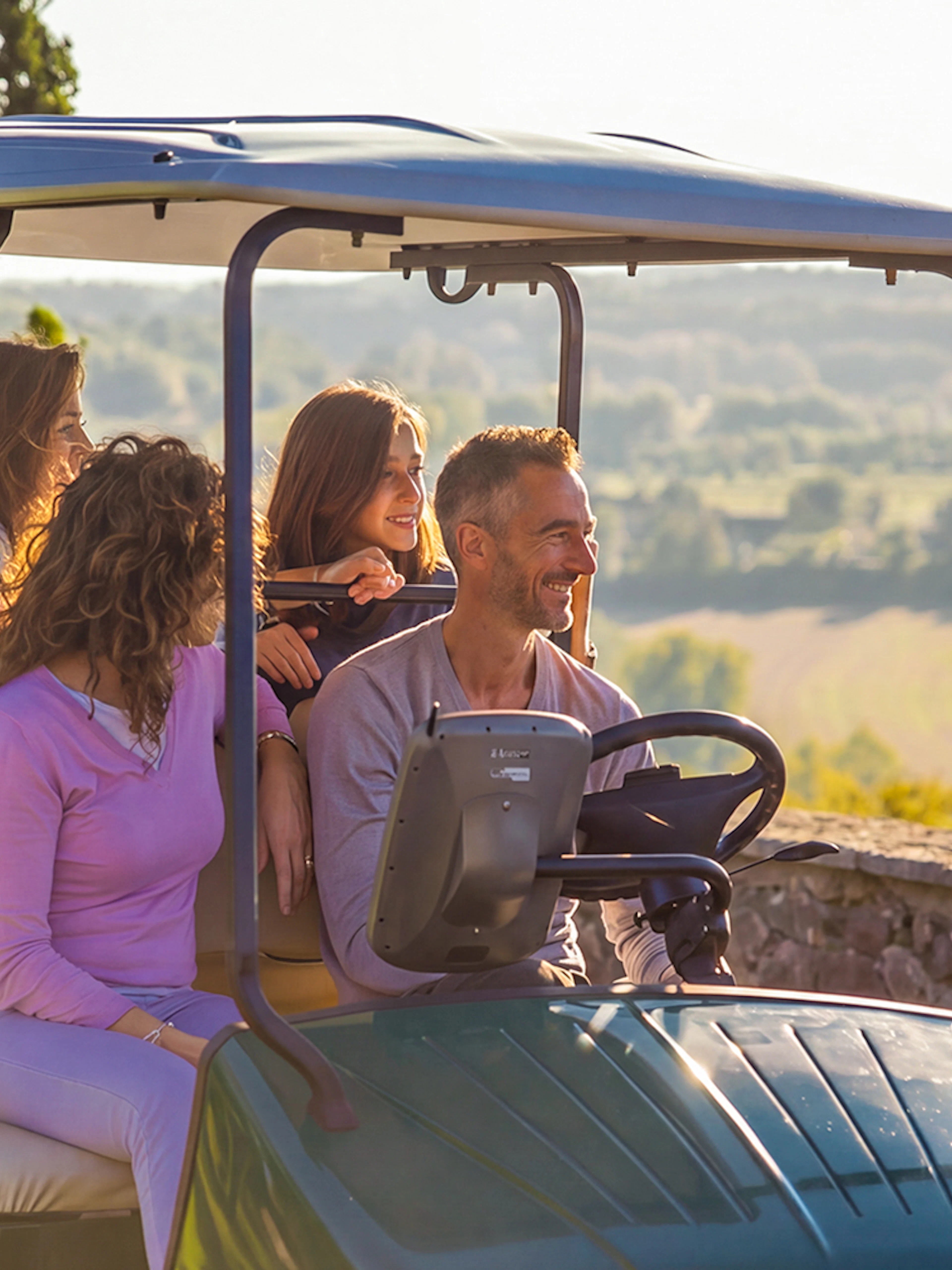 Golf cart tour at Parco Giardino Sigurtà with scenic landscape in background.