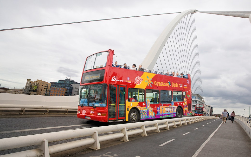 Open-top tour bus crossing Samuel Beckett Bridge over River Liffey in Dublin.