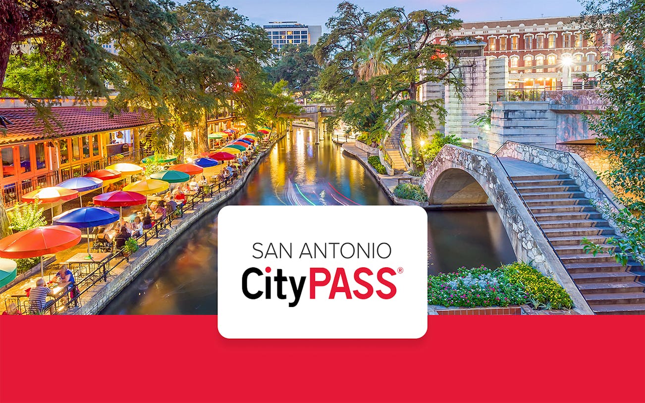 San Antonio River Walk with colorful umbrellas and stone bridge.