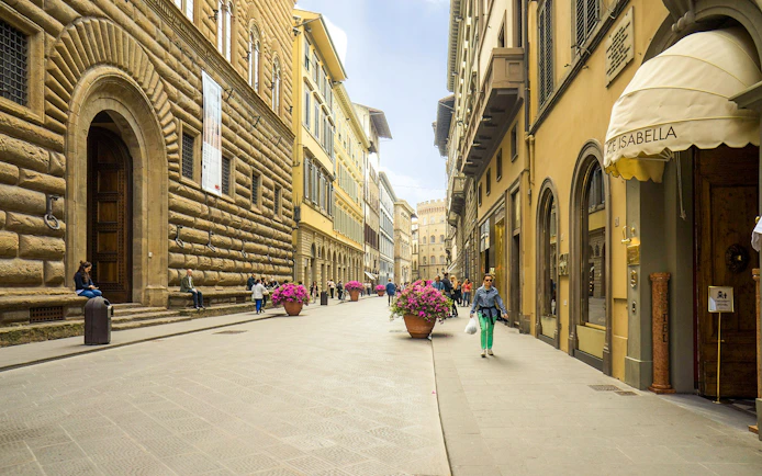 Street view near Palazzo Strozzi, Florence, Italy, with people walking and historic architecture.