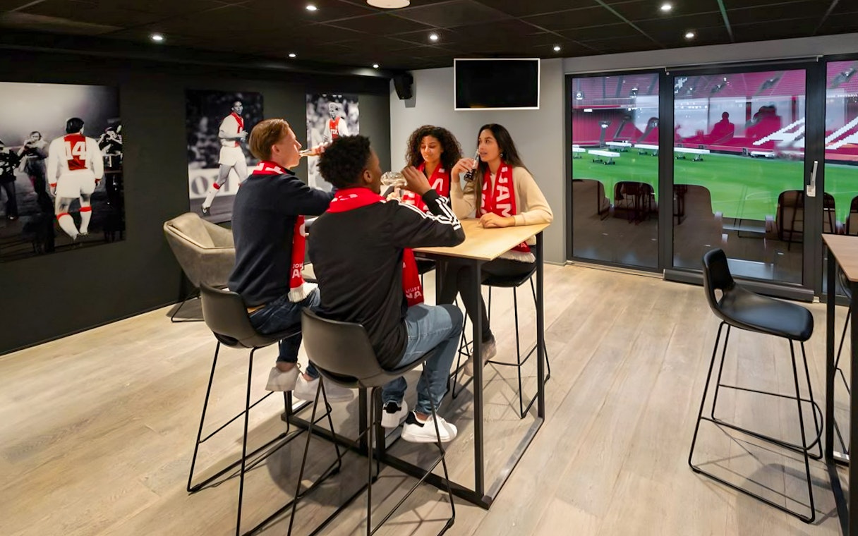 Visitors enjoying drinks and a view of the field during a VIP tour at Johan Cruijff ArenA, Amsterdam.