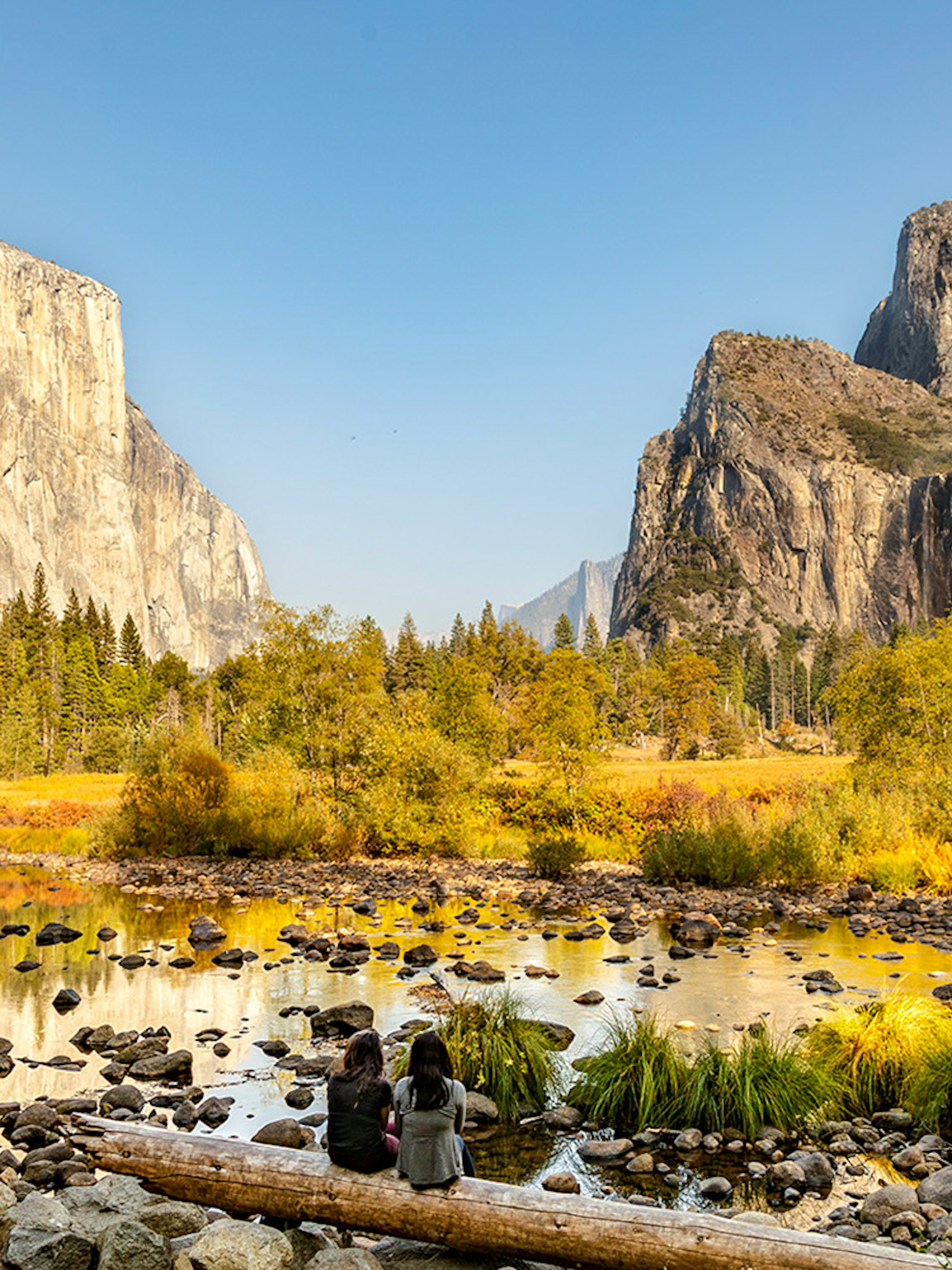 El Capitan and Yosemite Valley in autumn with people sitting by the river.