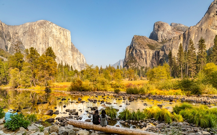El Capitan and Yosemite Valley in autumn with people sitting by the river.