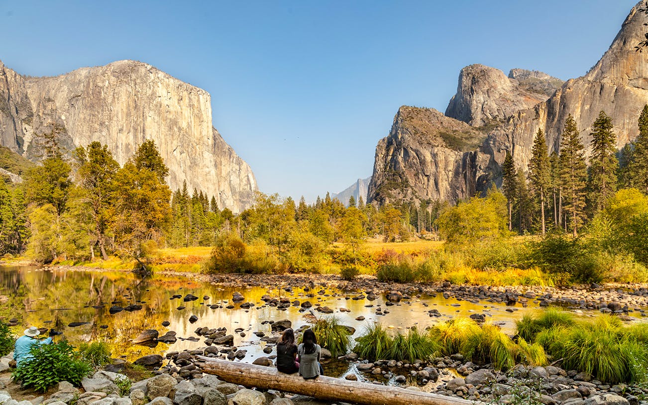 El Capitan and Yosemite Valley in autumn with people sitting by the river.