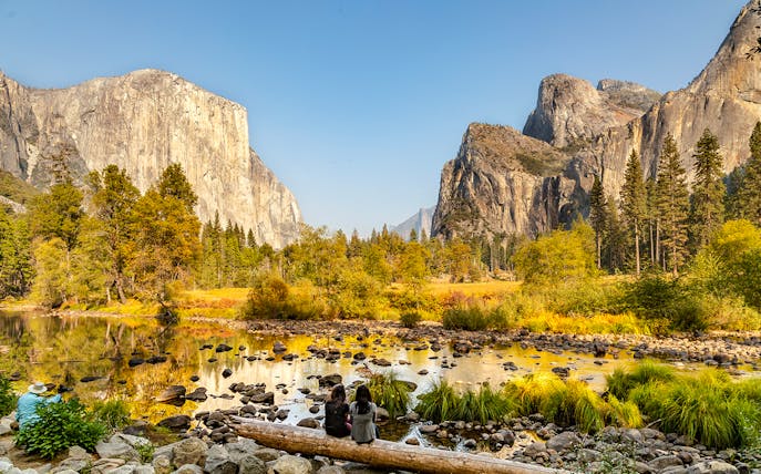 El Capitan and Yosemite Valley in autumn with people sitting by the river.