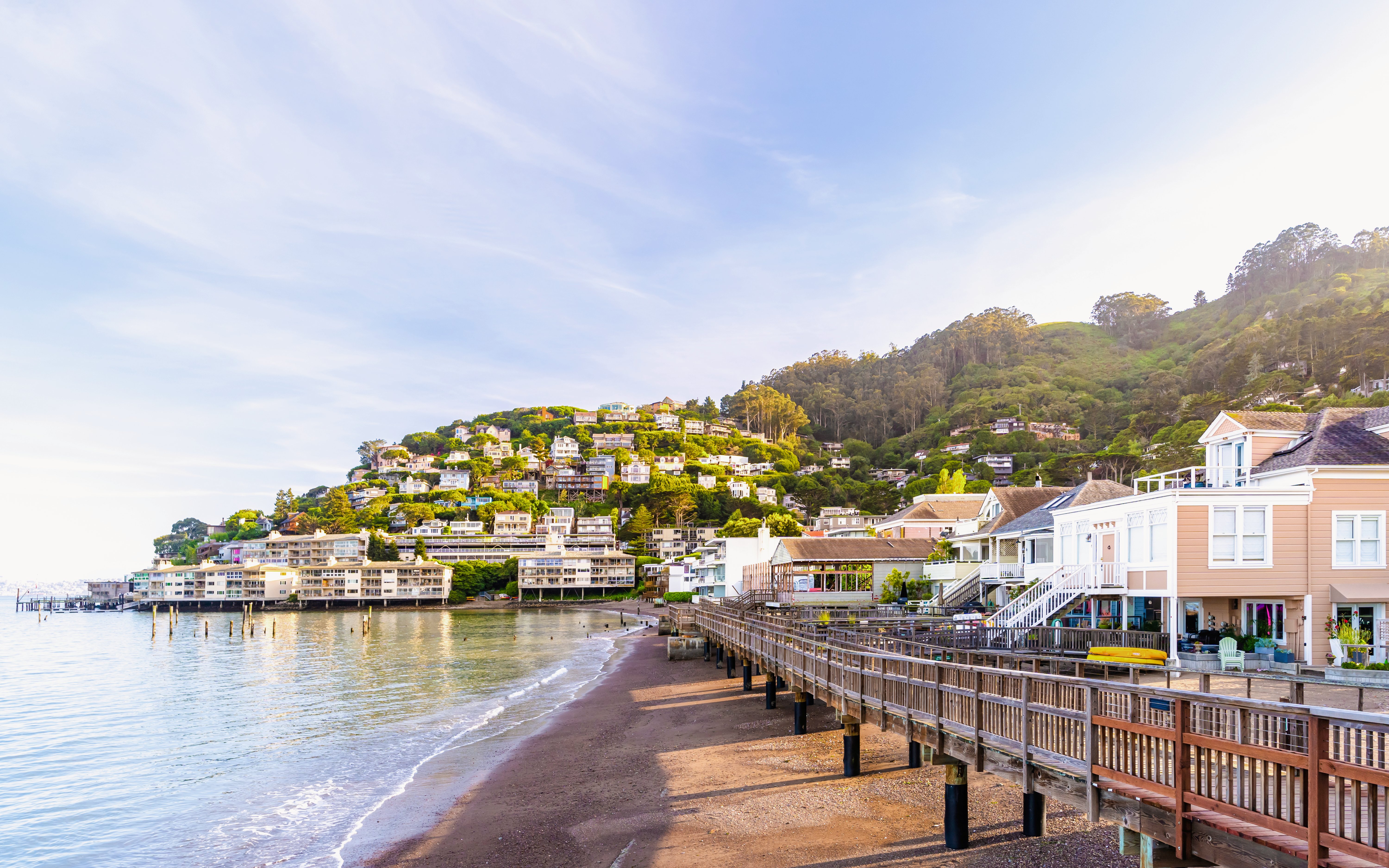 Sausalito waterfront with hillside homes and boardwalk in resort town.