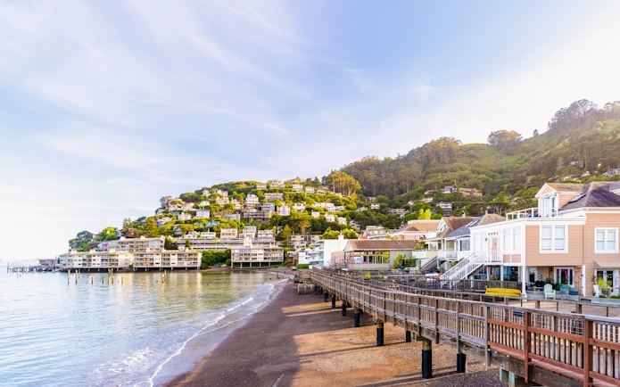 Sausalito waterfront with hillside homes and boardwalk in resort town.