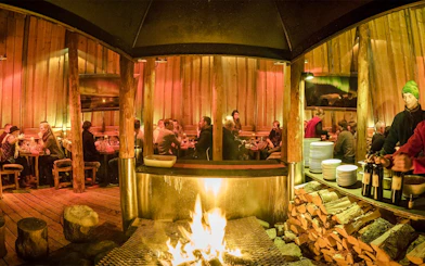 Guests dining inside a traditional Gamme hut with a central fire, Alaskan Husky Visit.
