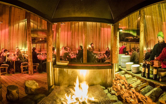 Guests dining inside a traditional Gamme hut with a central fire, Alaskan Husky Visit.