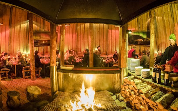 Guests dining inside a traditional Gamme hut with a central fire, Alaskan Husky Visit.