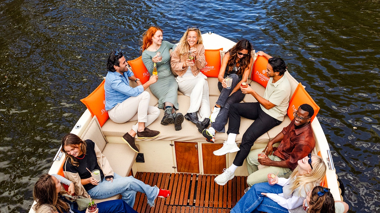 Guests enjoying drinks on a luxury open boat cruise in Amsterdam canal.
