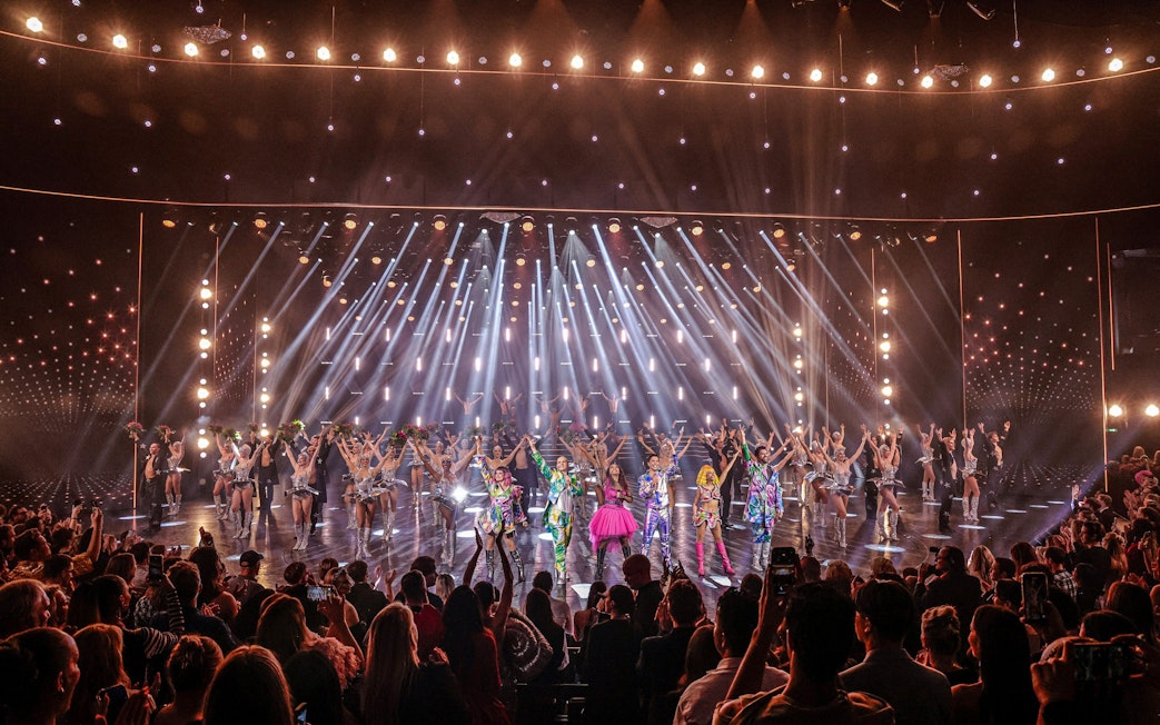 Performers on stage at Friedrichstadt Palast, Berlin, with vibrant costumes and lighting effects.