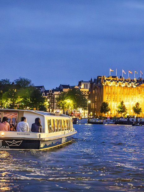 Winter evening canal cruise in Amsterdam with illuminated buildings.
